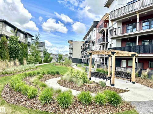 Landscaped courtyard featuring a pergola with two benches, a paved pathway, and varied plantings - 318 1506 Tamarack Boulevard, Edmonton, AB 