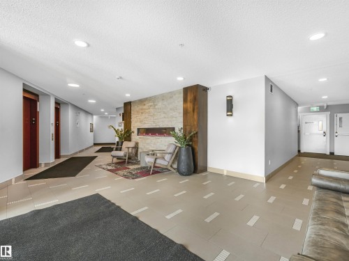 Inviting common area featuring an integrated linear fireplace with stone surround, recessed lighting, and tile flooring with accent detailing - 318 1506 Tamarack Boulevard, Edmonton, AB 
