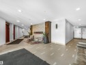 Inviting common area featuring an integrated linear fireplace with stone surround, recessed lighting, and tile flooring with accent detailing - 318 1506 Tamarack Boulevard, Edmonton, AB 