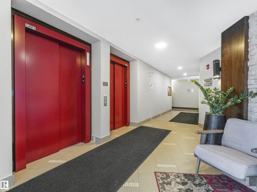 Elevator lobby featuring two red elevators, light tile flooring, and recessed lighting - 318 1506 Tamarack Boulevard, Edmonton, AB 