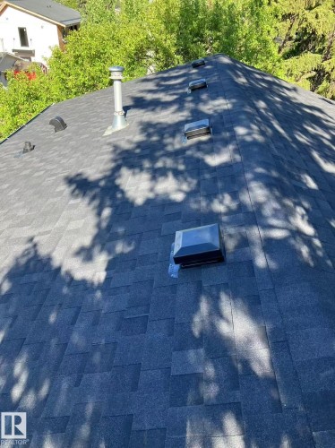 Dark gray asphalt shingle roof with multiple roof vents and a metal chimney - 10948 75 Avenue, Edmonton, AB 