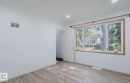 Bright room featuring light wood-finish flooring, recessed ceiling lighting, and a large multi-pane window with wood-trim framing - 10948 75 Avenue, Edmonton, AB 