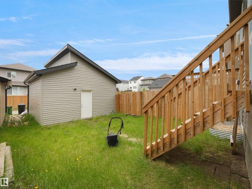 Spacious backyard featuring a detached garage with vinyl siding and a side entry door - 5022 Kinney Link Sw, Edmonton, AB 