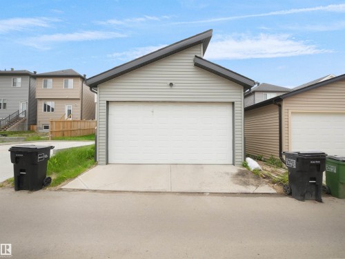 Detached single-car garage featuring light gray horizontal siding and a white panel garage door - 5022 Kinney Link Sw, Edmonton, AB 