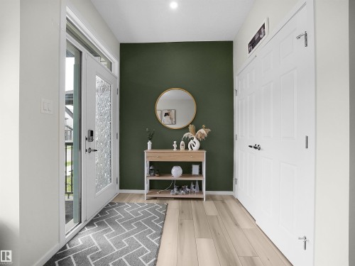 Entryway featuring a decorative accent wall, light wood-finish flooring, and a white paneled closet - 5022 Kinney Link Sw, Edmonton, AB 