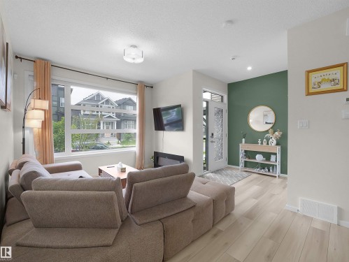 Bright living space featuring large windows, wood-finish flooring, recessed lighting, and a modern ceiling fixture - 5022 Kinney Link Sw, Edmonton, AB 