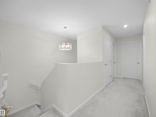 Upper-level hallway featuring light-toned walls, gray carpet flooring, and white paneled doors - 5022 Kinney Link Sw, Edmonton, AB 