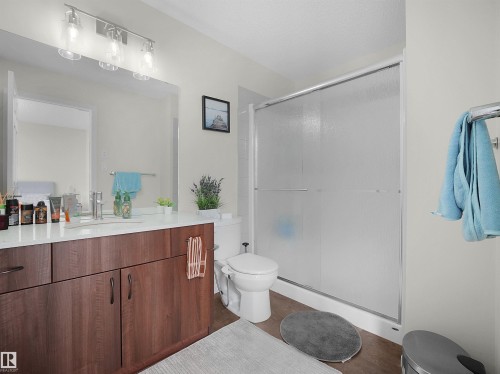Bathroom featuring a wood-finish vanity with a white countertop, an integrated sink, and a large wall-mounted mirror - 5022 Kinney Link Sw, Edmonton, AB 