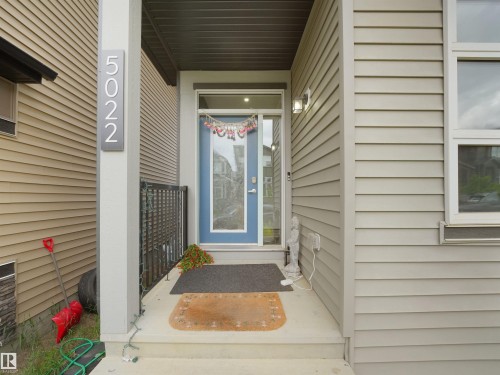 Front entry featuring a contemporary blue door with frosted glass paneling, a full-lite sidelight, and a transom window - 5022 Kinney Link Sw, Edmonton, AB 