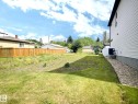 Expansive side yard featuring a partial lawn, gravel bed, and white vinyl siding - 9551 85 Street, Edmonton, AB 