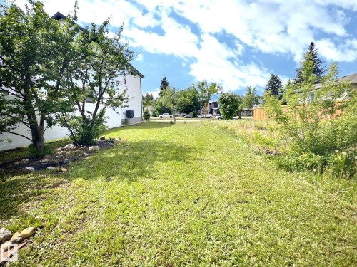 Spacious grassy yard with established trees and a white privacy fence - 9551 85 Street, Edmonton, AB 