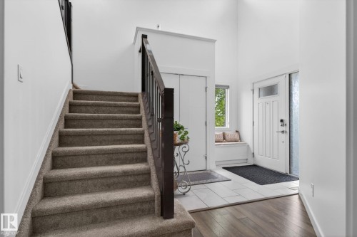 Inviting entryway featuring a white paneled front door with decorative glass, a built-in window seat, and contrasting tile and wood-finish flooring - 704 39 Street, Edmonton, AB 