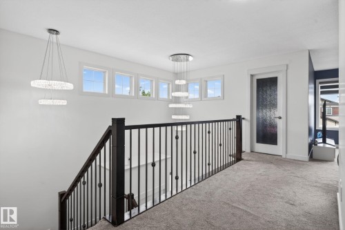 Upper landing with plush carpet flooring, dark wood newel posts, and decorative metal balusters - 704 39 Street, Edmonton, AB 
