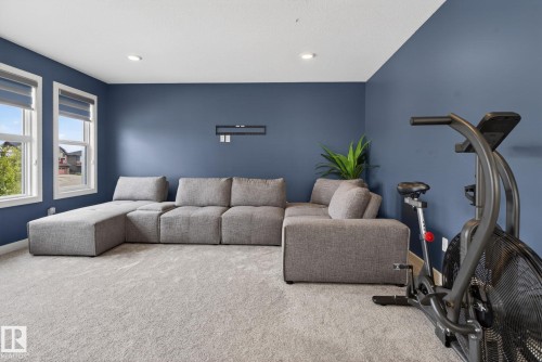 Spacious room featuring light gray carpet flooring, blue accent walls, and recessed lighting - 704 39 Street, Edmonton, AB 