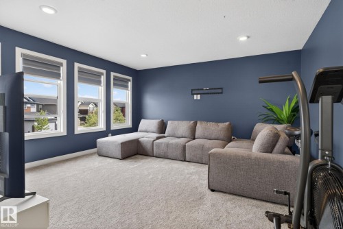 Carpeted room featuring a dark accent wall, three large windows with roller shades, and recessed lighting - 704 39 Street, Edmonton, AB 