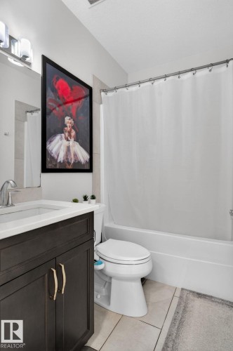 Bathroom featuring a dark wood-finish vanity with gold-tone hardware, a white countertop with integrated sink, and a chrome faucet - 704 39 Street, Edmonton, AB 