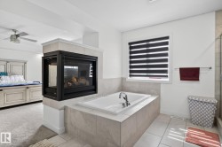 Two-sided fireplace featuring a tiled surround and an inset soaking tub with deck-mounted fixtures - 