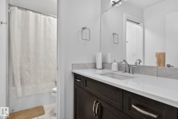 Bathroom featuring a dark wood vanity with a white countertop, undermount sink, and chrome faucet - 