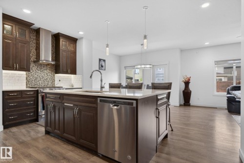 Kitchen featuring a large island with an undermount sink, stainless steel dishwasher, and pendant lighting - 704 39 Street, Edmonton, AB 
