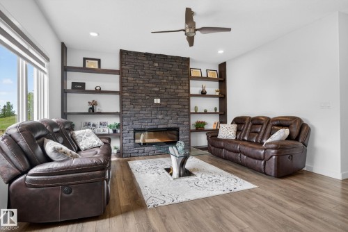 Living area featuring a floor-to-ceiling stone-clad fireplace with a linear insert, built-in shelving, wood-finish flooring, and recessed lighting - 704 39 Street, Edmonton, AB 