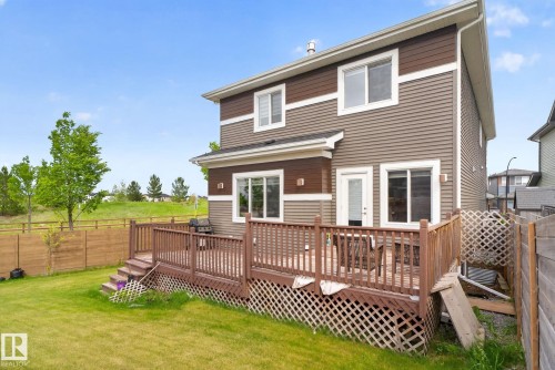 Two-story exterior featuring brown and tan siding, a spacious wood deck, and a green lawn - 704 39 Street, Edmonton, AB 