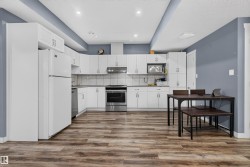 Kitchen featuring white cabinetry, wood-finish flooring, stainless steel appliances, recessed lighting, and a neutral tile backsplash - 