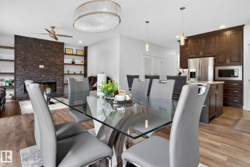 Dining area featuring wood-finish flooring, a contemporary glass-top table, and an ornate crystal chandelier - 704 39 Street, Edmonton, AB 