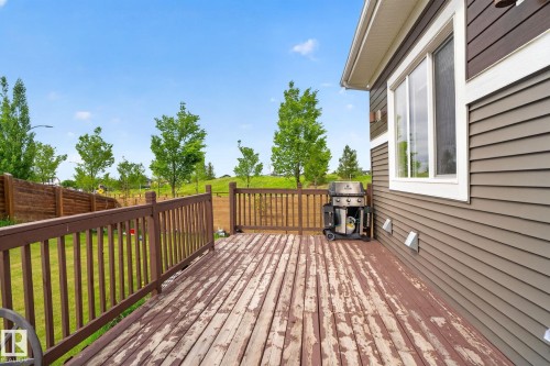 Wood deck with a brown railing, beige siding, white trim, and a window - 704 39 Street, Edmonton, AB 