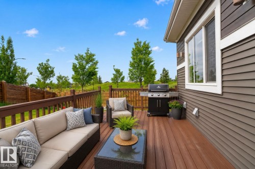Expansive outdoor deck featuring wood-finish flooring, a full railing system, and direct access to the interior via a large window opening - 704 39 Street, Edmonton, AB 