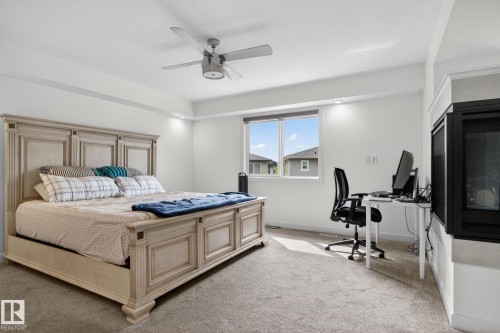 Recessed lighting illuminates this carpeted room featuring a ceiling fan, a window, and a built-in fireplace with a television recess above - 704 39 Street, Edmonton, AB 