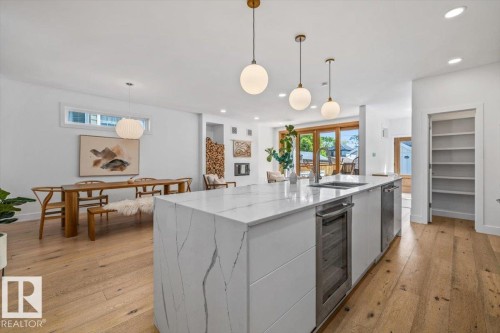 Spacious kitchen island with a waterfall countertop, integrated beverage cooler, and undermount sink - 10641 126 Street, Edmonton, AB 