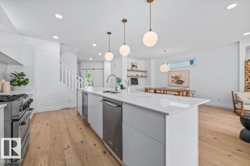 Open-concept kitchen featuring a large island with white stone countertops, integrated dishwasher, and beverage cooler - 10641 126 Street, Edmonton, AB 