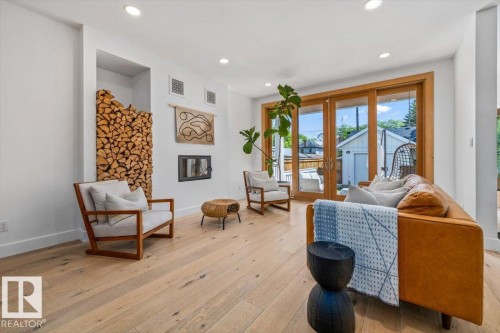 Recessed lighting illuminates wood-finish flooring, a built-in fireplace, and a wood-storage alcove - 10641 126 Street, Edmonton, AB 