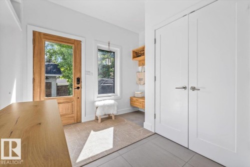 Entryway featuring a wood-finish door with a full-light panel, a side window, built-in shelving, and white bi-fold closet doors - 10641 126 Street, Edmonton, AB 