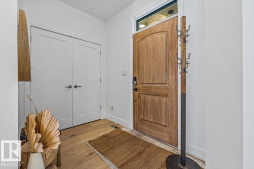 Wood-finish flooring and a natural wood-panel entry door with an overhead transom window - 10641 126 Street, Edmonton, AB 
