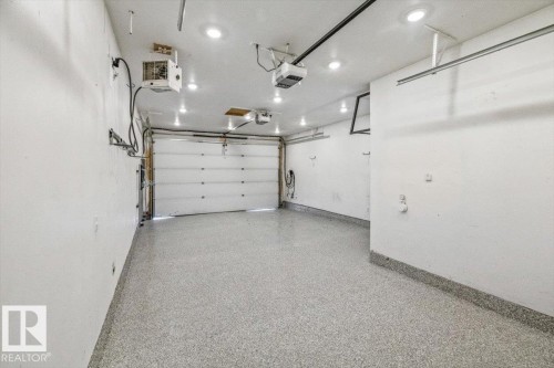 Spacious garage featuring a durable epoxy floor, recessed ceiling lighting, and overhead garage door opener system - 10641 126 Street, Edmonton, AB 