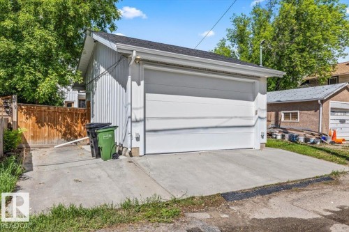 Detached garage with a white panel door, white vertical siding, and a dark shingle roof - 10641 126 Street, Edmonton, AB 