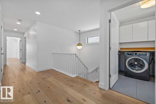 Upper-level hallway featuring wood-finish flooring, recessed lighting, and a modern spherical pendant light - 10641 126 Street, Edmonton, AB 