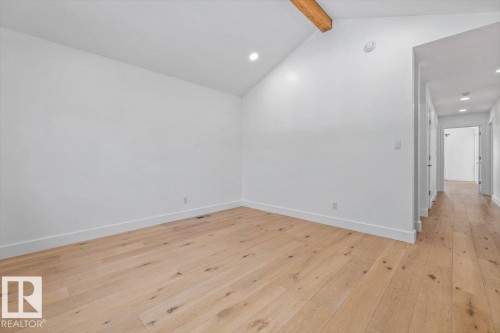 Bright interior space featuring vaulted ceilings, a prominent exposed wood beam, recessed lighting, and light wood-finish flooring - 10641 126 Street, Edmonton, AB 