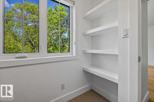 White-framed window with grid panes, built-in shelving, white baseboards, and neutral wall paint - 10641 126 Street, Edmonton, AB 