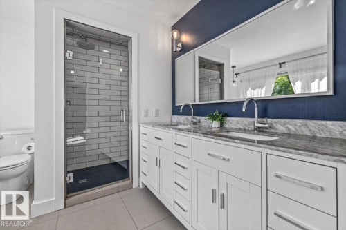 Bathroom featuring a double vanity with white cabinetry and a stone countertop - 10641 126 Street, Edmonton, AB 