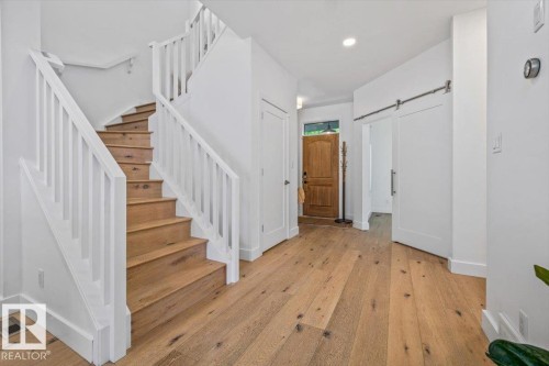 Hardwood flooring extending throughout the entry and staircase, featuring a white spindle railing - 10641 126 Street, Edmonton, AB 