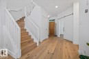 Hardwood flooring extending throughout the entry and staircase, featuring a white spindle railing - 10641 126 Street, Edmonton, AB 