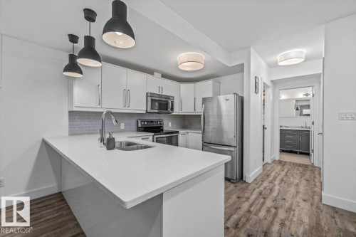Modern kitchen featuring white cabinetry, stainless steel appliances, and a light-toned countertop - 10641 126 Street, Edmonton, AB 
