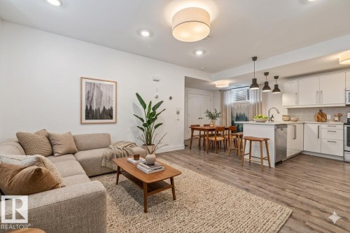 Open-concept living space featuring wood-finish flooring, recessed lighting, white kitchen cabinetry with a tile backsplash, and an island with pendant lighting - 10641 126 Street, Edmonton, AB 