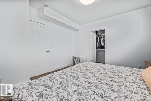 Bedroom featuring wood-finish flooring, white walls, and a built-in closet with shelving and hanging storage - 10641 126 Street, Edmonton, AB 