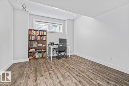 Spacious interior room featuring wood-finish flooring, light-toned walls, a single window with blinds, and recessed lighting - 10641 126 Street, Edmonton, AB 