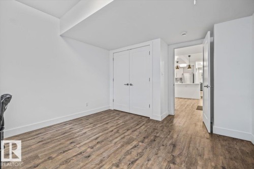 Room featuring wood-finish flooring, white walls, and a recessed ceiling element - 10641 126 Street, Edmonton, AB 