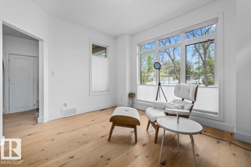 Bright interior space featuring wood-finish flooring, white baseboards, and a large multi-pane window - 10641 126 Street, Edmonton, AB 