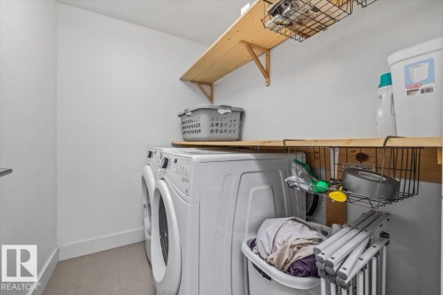 Dedicated laundry area featuring a stackable washer and dryer, light wood-finish shelving, and a durable flooring surface - 10641 126 Street, Edmonton, AB 